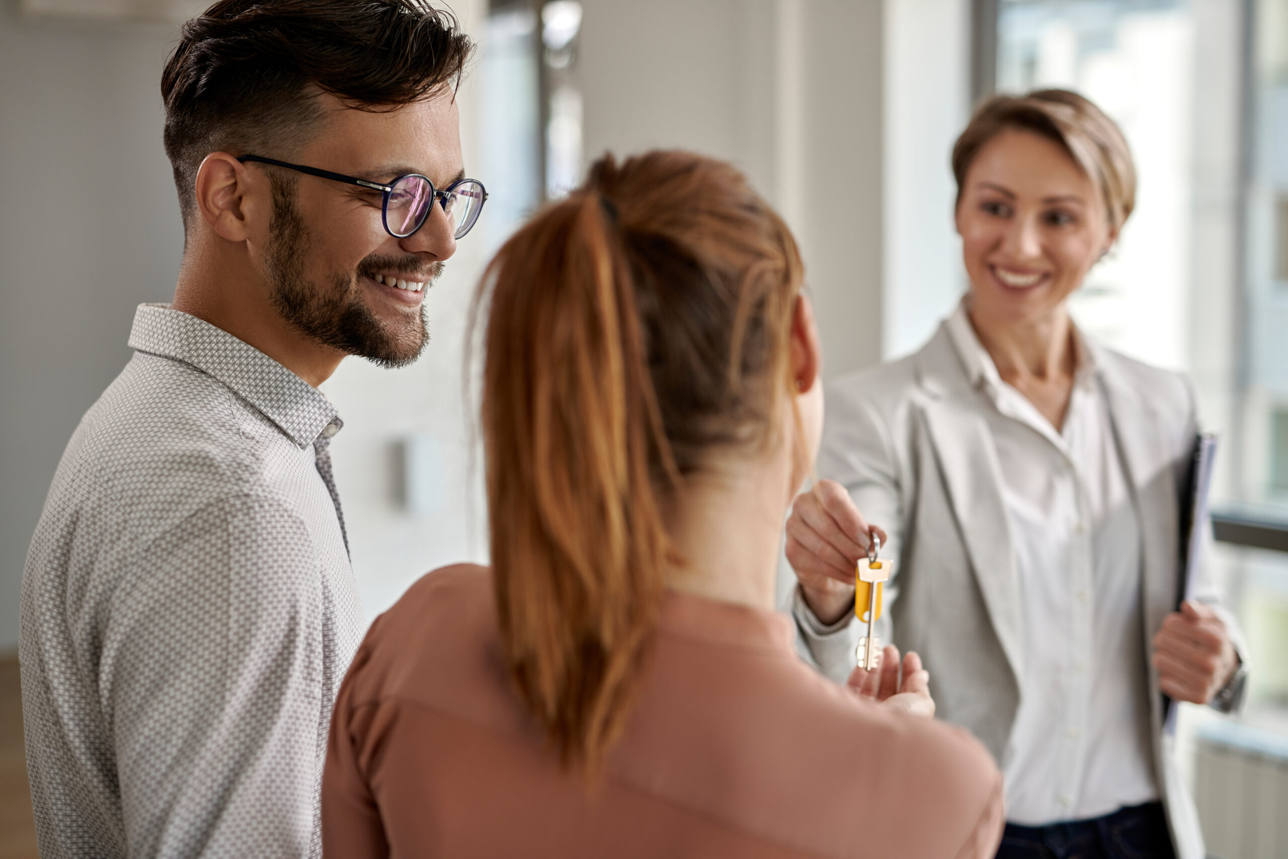 زوجان شابان يتناقشان مع وكيل عقاري قبل قرار شراء الشقة – أفضل وقت لشراء شقة للشباب